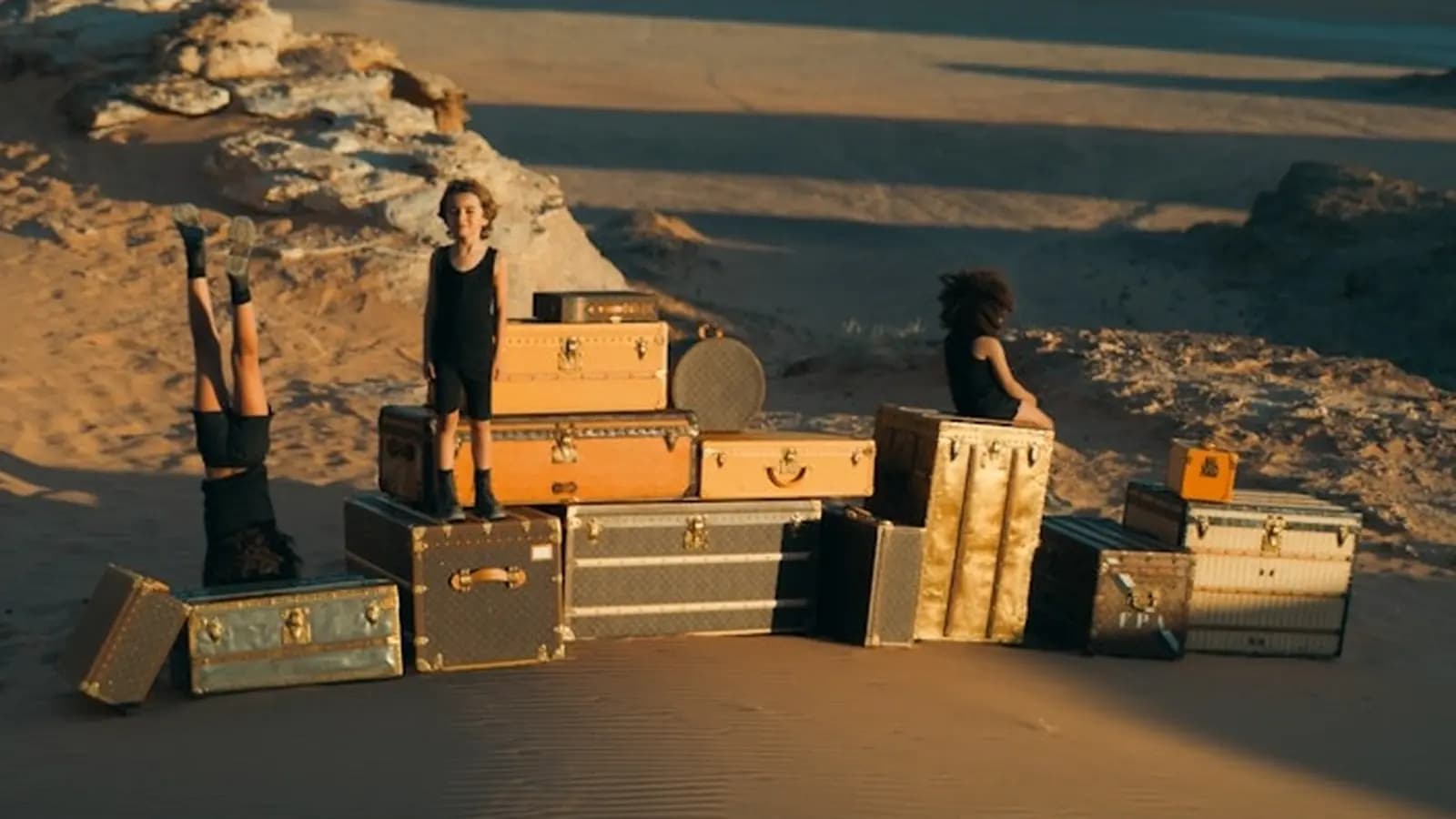 Louis Vuitton Towards a Dream poster showing children among stacked trunks in a desert landscape.