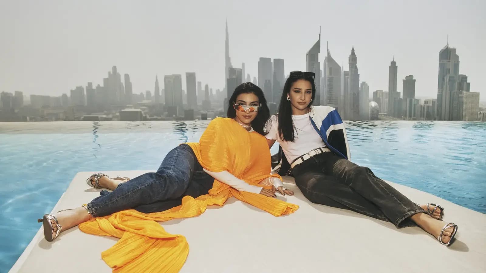 One&Only Our City, No Limits poster showing two women reclining by an infinity pool with a city skyline in the background.