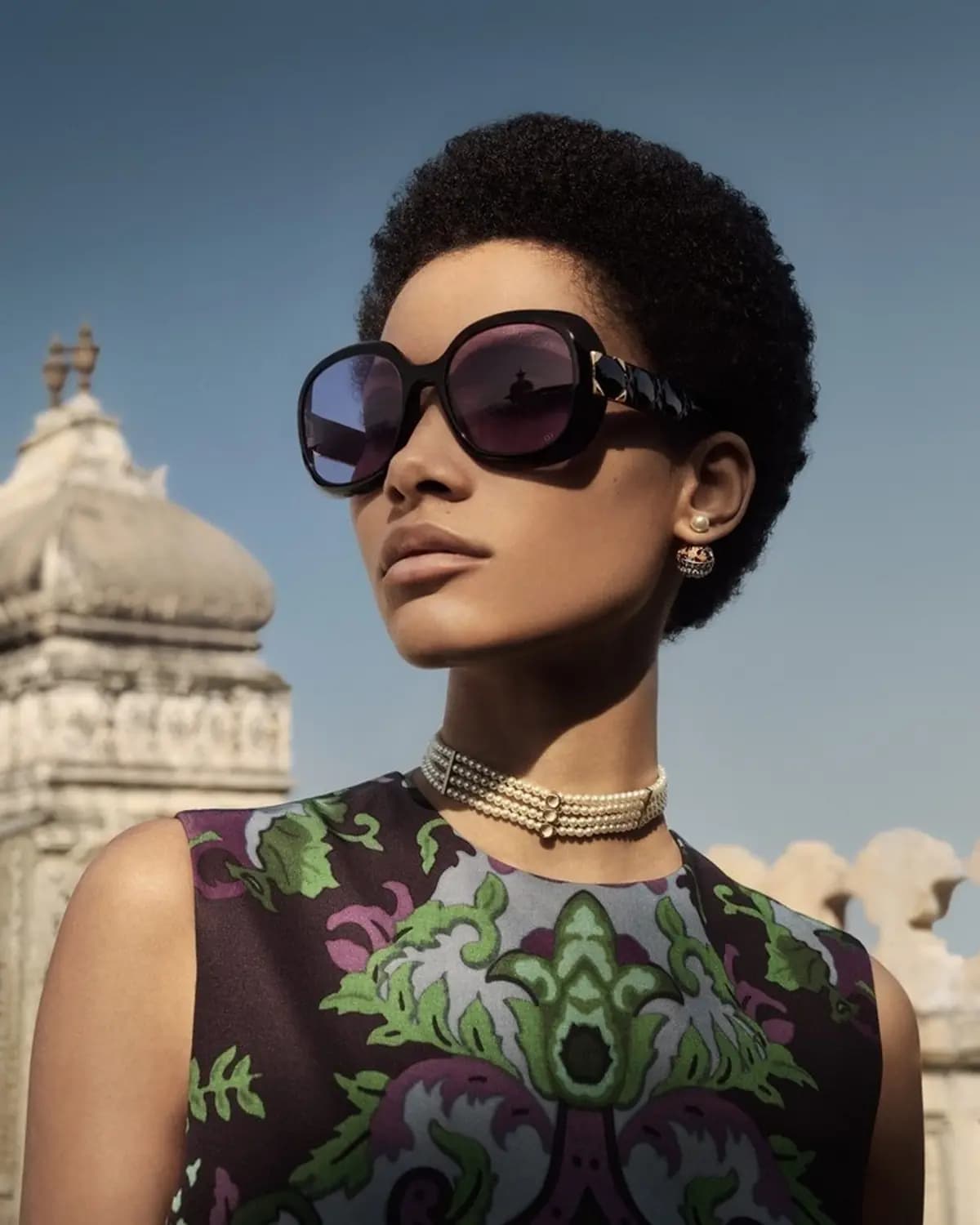 Dior Fall Women's Campaign poster showing a fashion model wearing sunglasses and jewellery against an architectural backdrop.